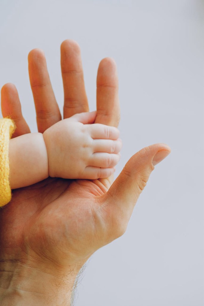 Image of a young child’s hand resting inside their mother’s to signify how early childhood development affects personality and mental health.